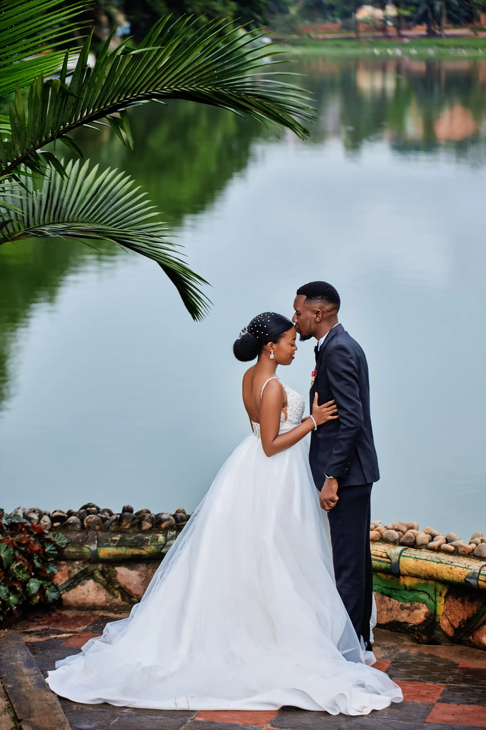 Bride and groom embracing beside a lake