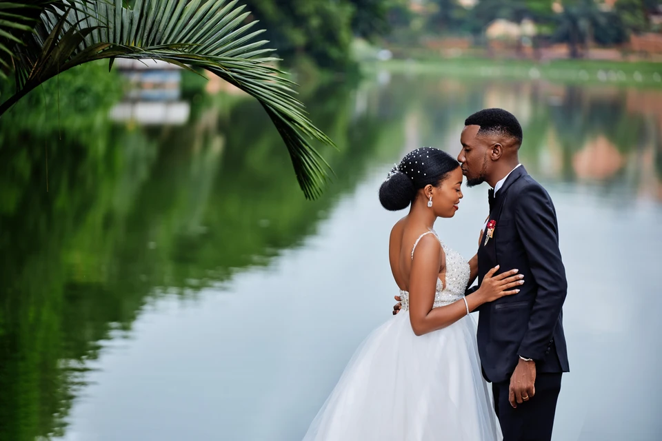 Bride and groom sharing a kiss beside a lake